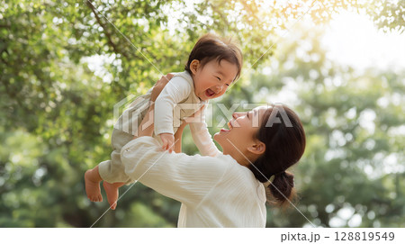 緑の中で赤ちゃんを高く抱き上げて微笑む母親「生成AI」 緑の中で赤ちゃんを高く抱き上げて微笑む母親「生成AI」 128819549