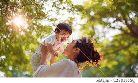 緑の中で赤ちゃんを高く抱き上げて微笑む母親「生成AI」 緑の中で赤ちゃんを高く抱き上げて微笑む母親「生成AI」 128819550