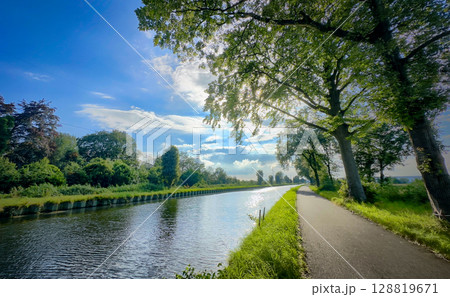A Serene and Beautiful Canal View Surrounded by Lush Greenery Beneath a Bright Blue Sky 128819671