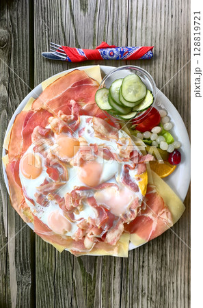 A Delicious and Appetizing Breakfast Plate Featuring Eggs, Ham, and Various Toppings 128819721