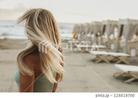 Blonde Woman Turning on Beach in Summer Breeze Blonde Woman Turning on Beach in Summer Breeze 128819780