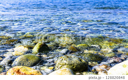 青く透き通った海の波が浜辺に穏やかに押し寄せる写真 128820848
