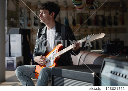 A man plays electric guitar in a music store 128821561
