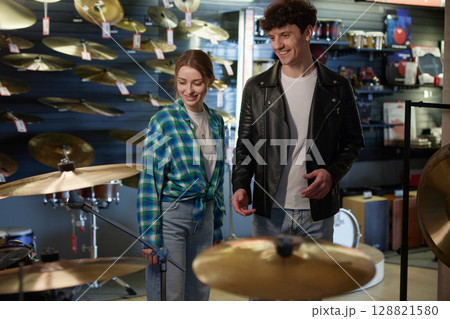 A man and a woman are leisurely walking inside a music store, exploring 128821580