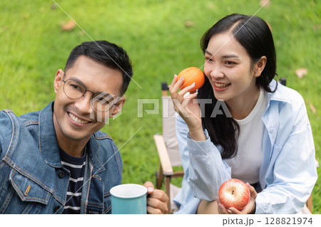Cheerful couple sharing healthy snacks in a garden Cheerful couple sharing healthy snacks in a garden 128821974