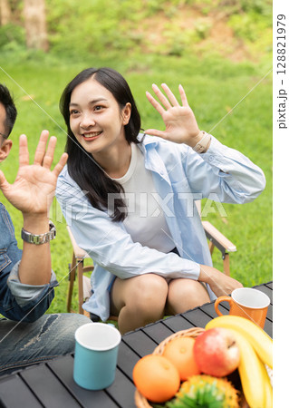 Happy couple waving and enjoying healthy snacks in a sunny garden. 128821979