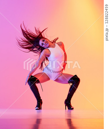 Jazz funk performer dressed in white attire wearing high heels with vibrant backdrop 128822459
