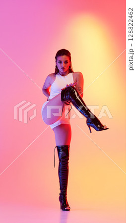 Vibrant lighting showcases dynamic pose with jazz funk and high heel fashion Vibrant lighting showcases dynamic pose with jazz funk and high heel fashion 128822462