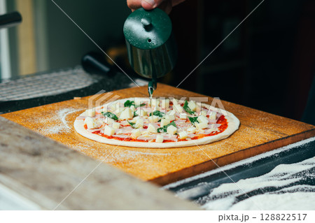 Chef Preparing Homemade Pizza with Ham and Basil 128822517