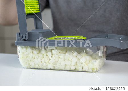 Efficient kitchen vegetable chopper in modern gray and neon green design holds perfectly diced white onions, simplifying quick, healthy meal preparation at home Efficient kitchen vegetable chopper in modern gray and neon green design holds perfectly diced white onions, simplifying quick, healthy meal preparation at home 128822936