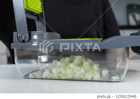 Practical kitchen vegetable chopper filled with freshly diced white onions, demonstrating an efficient tool for quick, convenient home meal preparation and healthy cooking Practical kitchen vegetable chopper filled with freshly diced white onions, demonstrating an efficient tool for quick, convenient home meal preparation and healthy cooking 128822946