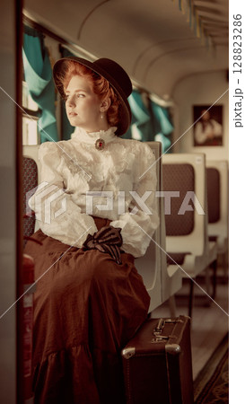 Woman in vintage outfit sitting on train with suitcase looking through window 128823286