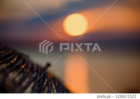 Sky with light clouds over the sea. In the foreground a bamboo sunshade. Sunset Sky with light clouds over the sea. In the foreground a bamboo sunshade. Sunset 128823322