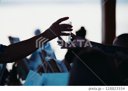 A waiter takes an empty glass from a customer. Silhouette. Summer evening A waiter takes an empty glass from a customer. Silhouette. Summer evening 128823334
