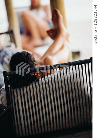 A young woman in a bright orange swimsuit relaxes at a table in a summer bar 128823344