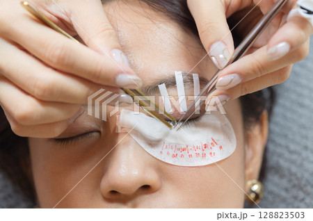 Young southeast asian woman receiving eyelashes extension procedure in beauty salon. Focus on female eyes health wellness and natural beauty for perfect beauty makeup look Young southeast asian woman receiving eyelashes extension procedure in beauty salon. Focus on female eyes health wellness and natural beauty for perfect beauty makeup look 128823503