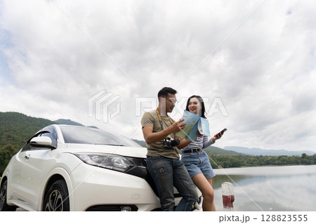 Couple exploring nature with map by car near lake Couple exploring nature with map by car near lake 128823555