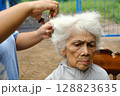 A caregiver is giving a haircut to an elderly woman. 128823635