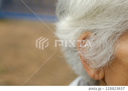 The elderly man's white hair is starting to grow long. 128823637