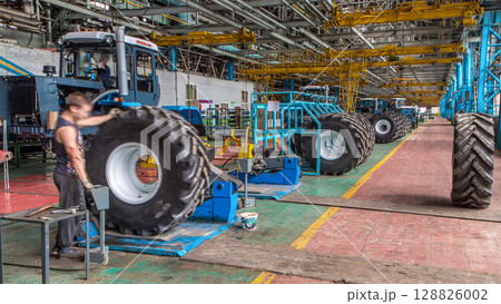 Professional mechanic install tire on wheel in repair service on tractor factory timelapse. 128826002