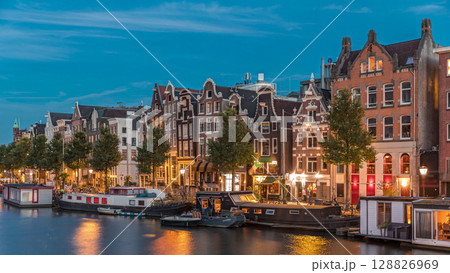 Panoramic timelapse hyperlapse of the illuminated famous Dancing Houses along the Amstel River day to night transition. Amsterdam, Netherlands 128826969