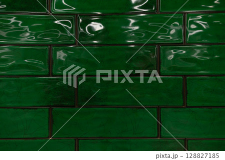 Rich green ceramic tiles create a vibrant and glossy wall surface in an indoor setting, enhancing 128827185