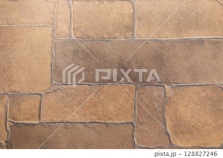Textured stone wall with warm earthy tones in a close-up view highlighting the natural patterns and 128827246