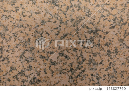 Textured granite surface with earthy tones and subtle patterns displayed in close-up view 128827760
