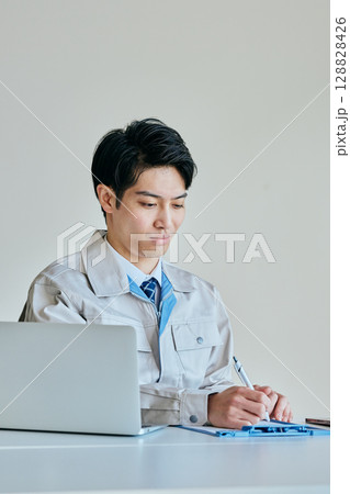 メモをとる作業服姿の若い男性 128828426