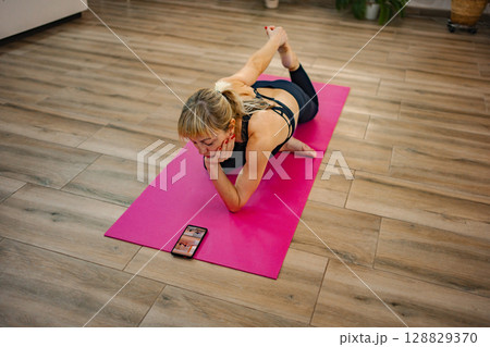 Practicing yoga at home while following an online class 128829370