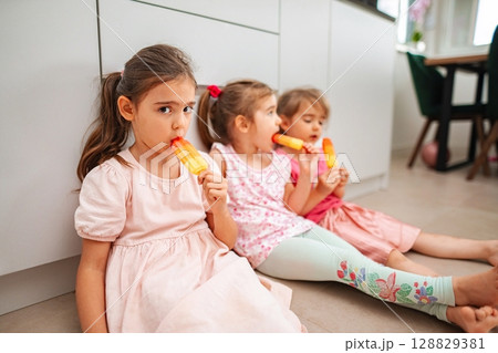Sisters enjoying colorful popsicles on a warm afternoon Sisters enjoying colorful popsicles on a warm afternoon 128829381