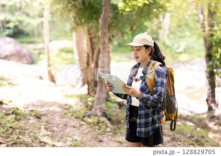 Hiker reading map in sunlit forest path Hiker reading map in sunlit forest path 128829705