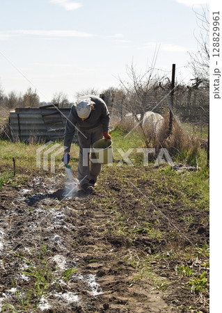 Young man engaged in household chores and small-scale rural farming, tending to his garden with care and dedication. His daily routine reflects a sustainable and self-sufficient way of life Young man engaged in household chores and small-scale rural farming, tending to his garden with care and dedication. His daily routine reflects a sustainable and self-sufficient way of life 128829961