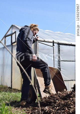 Young man engaged in household chores and small-scale rural farming, tending to his garden with care and dedication. His daily routine reflects a sustainable and self-sufficient way of life 128829967