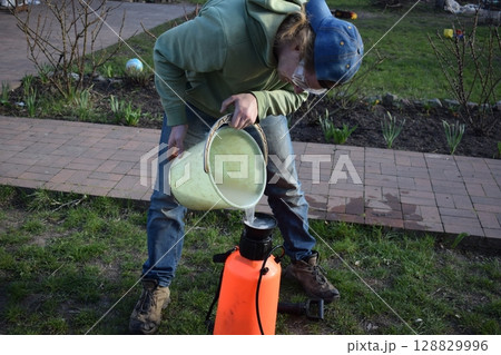 Young man engaged in household chores and small-scale rural farming, tending to his garden with care and dedication. His daily routine reflects a sustainable and self-sufficient way of life Young man engaged in household chores and small-scale rural farming, tending to his garden with care and dedication. His daily routine reflects a sustainable and self-sufficient way of life 128829996