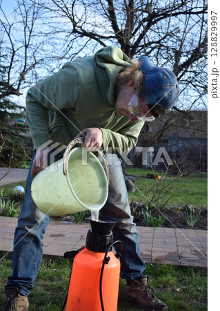Young man engaged in household chores and small-scale rural farming, tending to his garden with care and dedication. His daily routine reflects a sustainable and self-sufficient way of life 128829997
