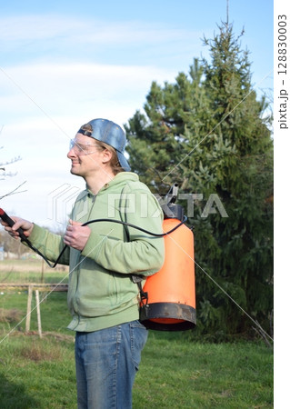 Young man engaged in household chores and small-scale rural farming, tending to his garden with care and dedication. His daily routine reflects a sustainable and self-sufficient way of life Young man engaged in household chores and small-scale rural farming, tending to his garden with care and dedication. His daily routine reflects a sustainable and self-sufficient way of life 128830003