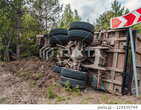 An overturned truck lies on its side off a rural road. An overturned truck lies on its side off a rural road. 128830744