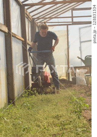 Young man engaged in household chores and small-scale rural farming, tending to his garden with care and dedication. His daily routine reflects a sustainable and self-sufficient way of life Young man engaged in household chores and small-scale rural farming, tending to his garden with care and dedication. His daily routine reflects a sustainable and self-sufficient way of life 128831334