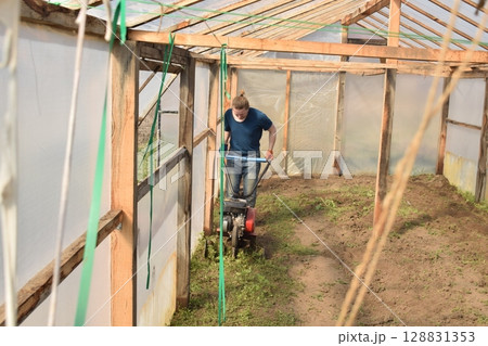 Young man engaged in household chores and small-scale rural farming, tending to his garden with care and dedication. His daily routine reflects a sustainable and self-sufficient way of life 128831353