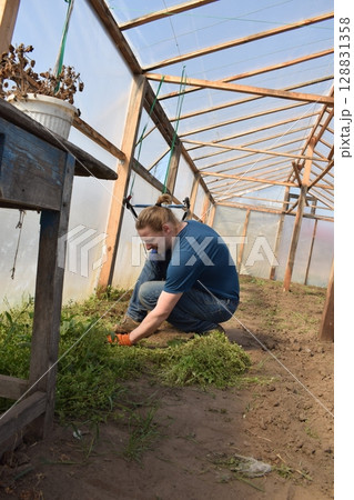 Young man engaged in household chores and small-scale rural farming, tending to his garden with care and dedication. His daily routine reflects a sustainable and self-sufficient way of life 128831358