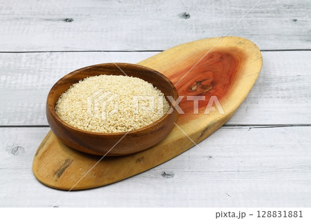 Top view closeup of freshly harvested white sesame in wooden bowl isolated on wooden background with clipping path. 128831881