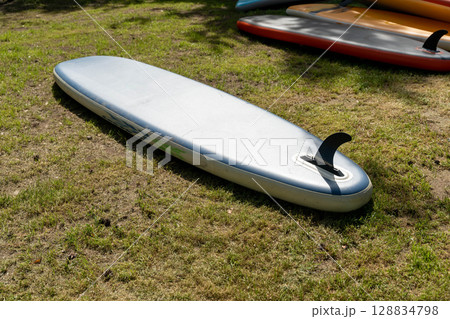 Inflatable stand up paddle board lying on grass in a sunny day Inflatable stand up paddle board lying on grass in a sunny day 128834798
