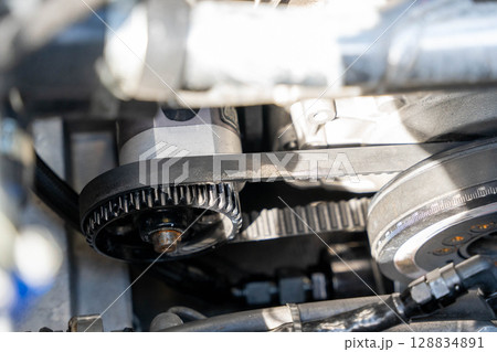 Close-up of timing belt and tensioner pulley in car engine Close-up of timing belt and tensioner pulley in car engine 128834891
