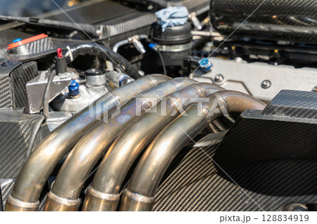 Exhaust manifold pipes emerging from powerful carbon fiber engine 128834919