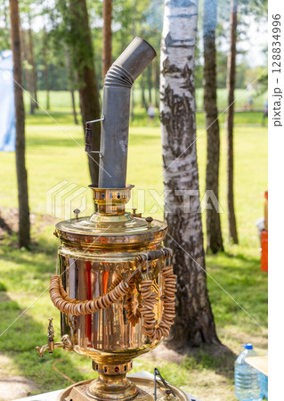 Traditional russian samovar brewing tea outdoors in summer Traditional russian samovar brewing tea outdoors in summer 128834996