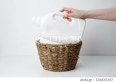 Laundry detergent branding mock up and basket filled with clean white towels. Household cleaning and hygiene concept packaging 128835307