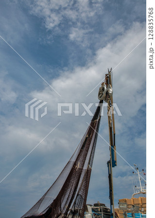 Fishing net hanging from boat mast against sky Fishing net hanging from boat mast against sky 128835768