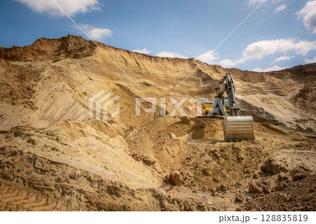 A caterpillar tractor works with a bucket in a sand pit. Sand mining 128835819