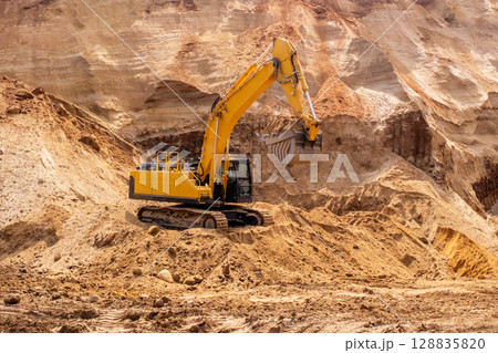A caterpillar tractor works with a bucket in a sand pit. Sand mining A caterpillar tractor works with a bucket in a sand pit. Sand mining 128835820